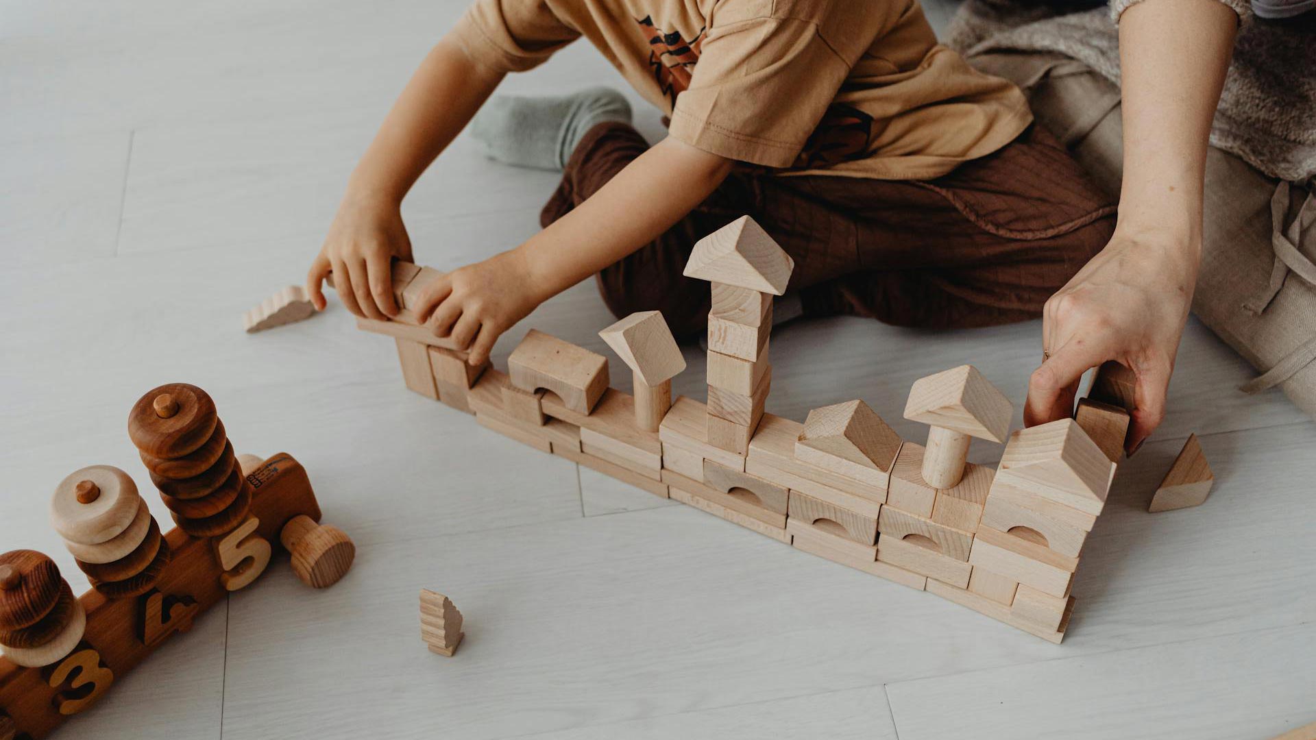 Erickson-2025-02-07-1 A kid and an adult play with wood blocks together.