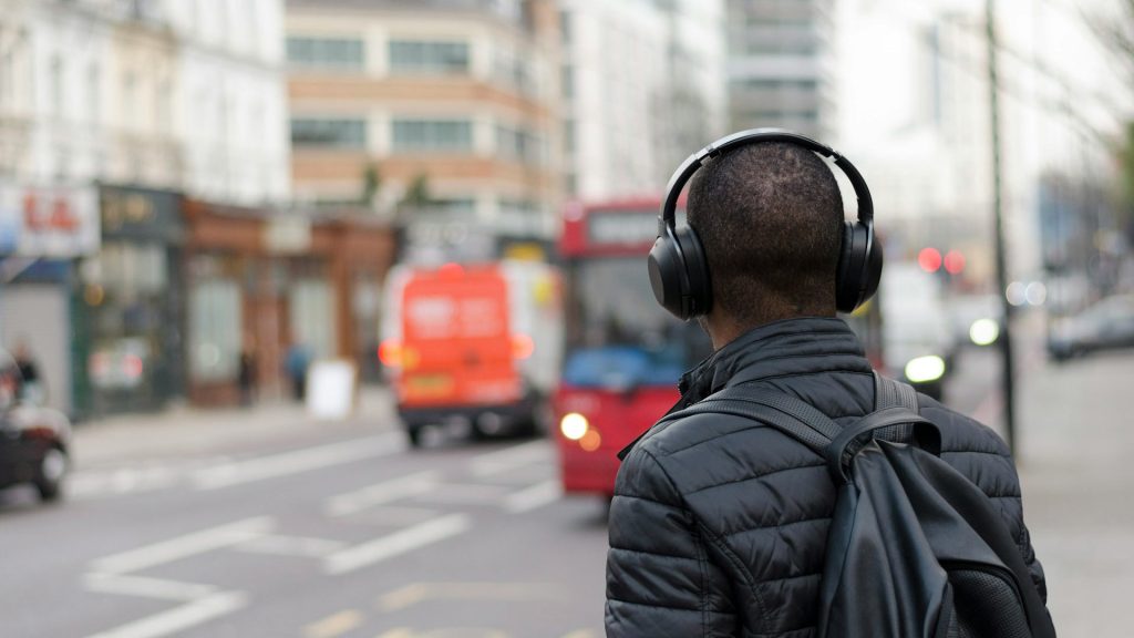 A person crosses the street with over-the-ear headphones on.