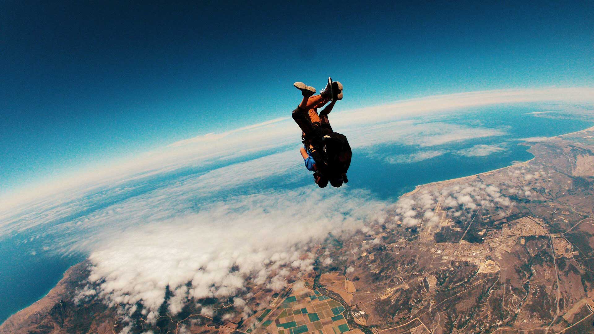 A person skydives high above the Earth.
