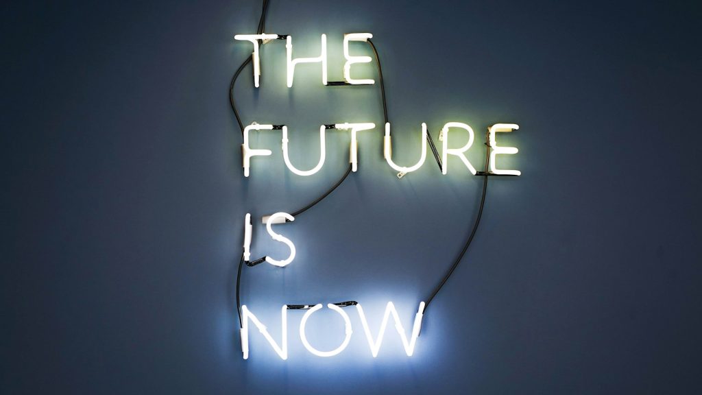 Neon lights spell out the sentence “The future is now.”