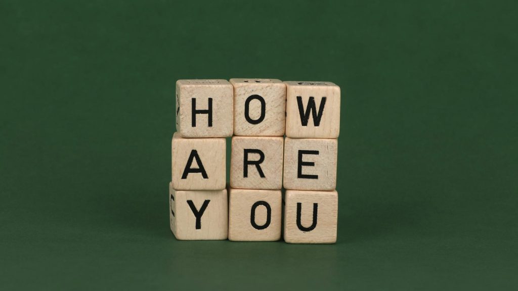 Wood blocks with black letters on them are stacked up to spell the phrase "How are you?"